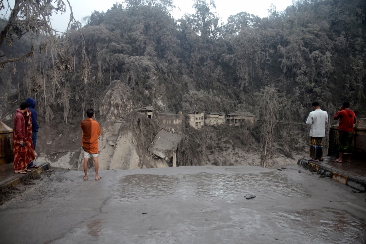 Habitantes de un pueblo cercano al volcán Semeru miran la destrucción tras la erupción.