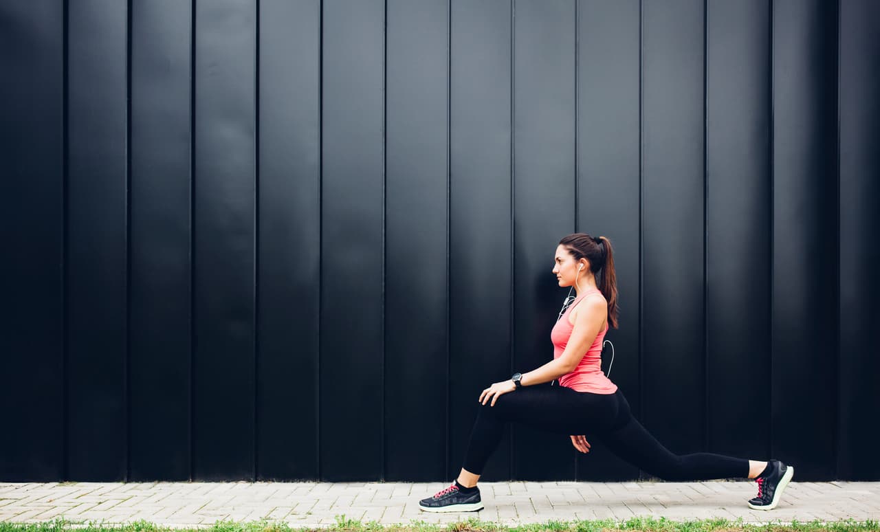 El último ejercicio es de pie. Toma una mancuerna y recárgala sobre tu hombro. Abre un poco las piernas y haz desplantes laterales. Realízalo con ambas extremidades, una a la vez.