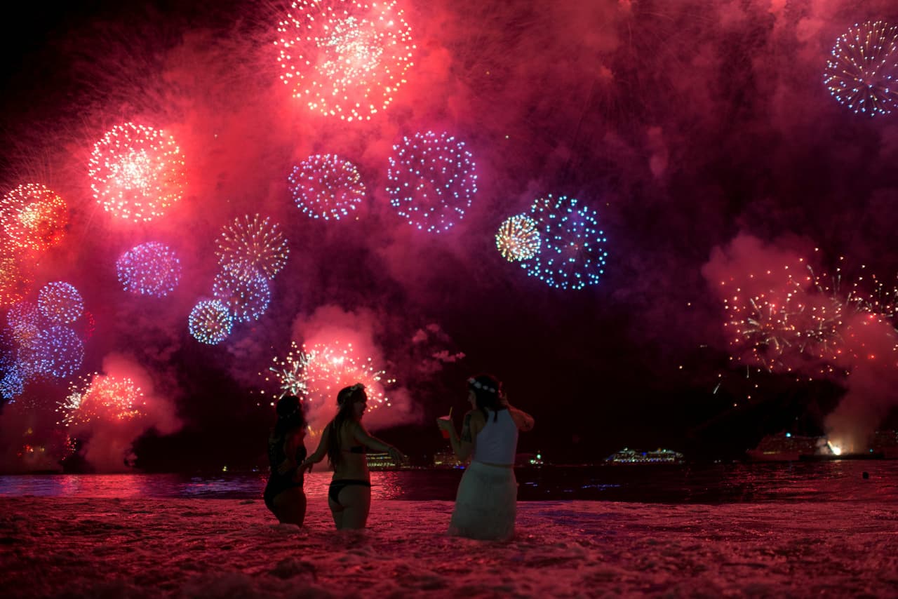 Desde la playa de Copacabana, en Ríos de Janeiro, Brasil, estas tres mujeres divisan el espectáculo de luces que anuncia la llegada de un nuevo año.