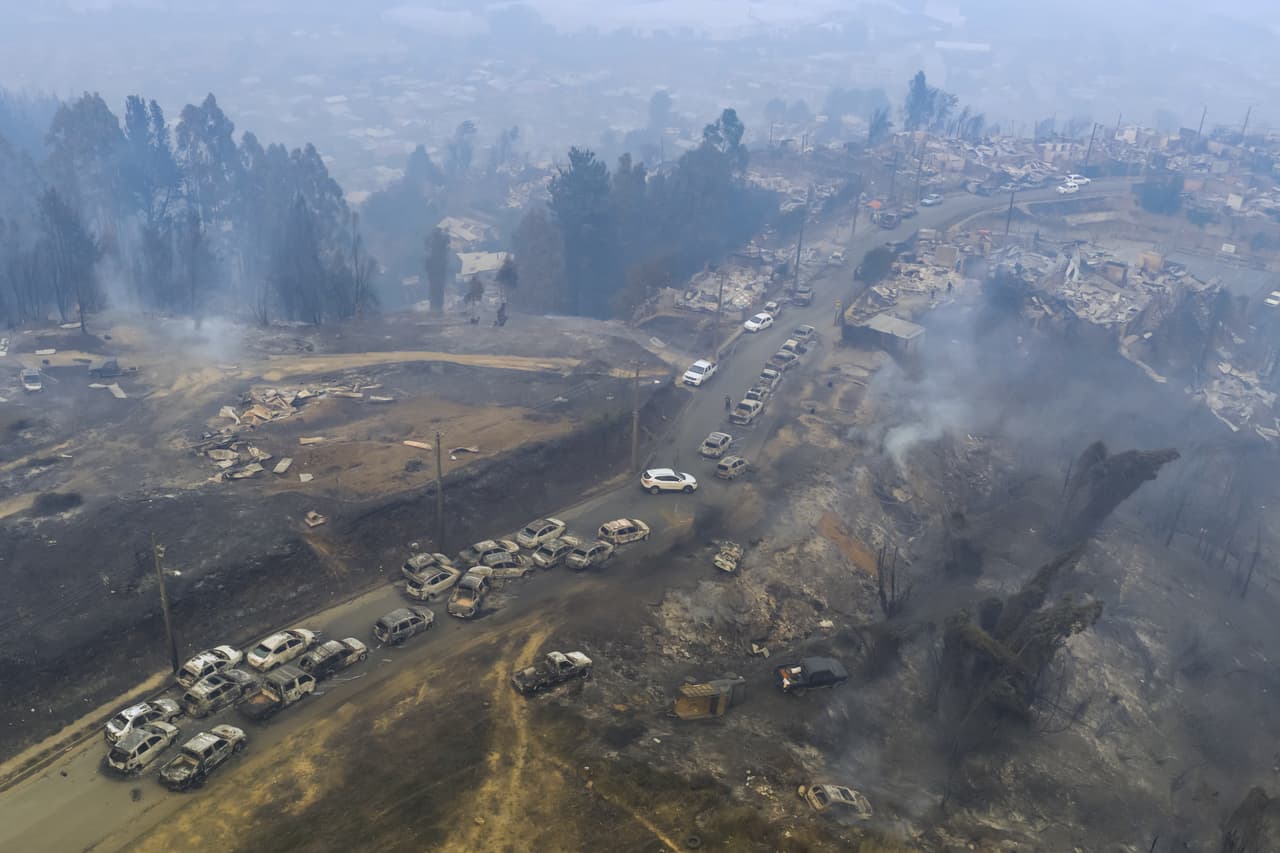 Una fila de carros dañados se alinean en una carretera luego de los incendios forestales en Lirquen, Chile.