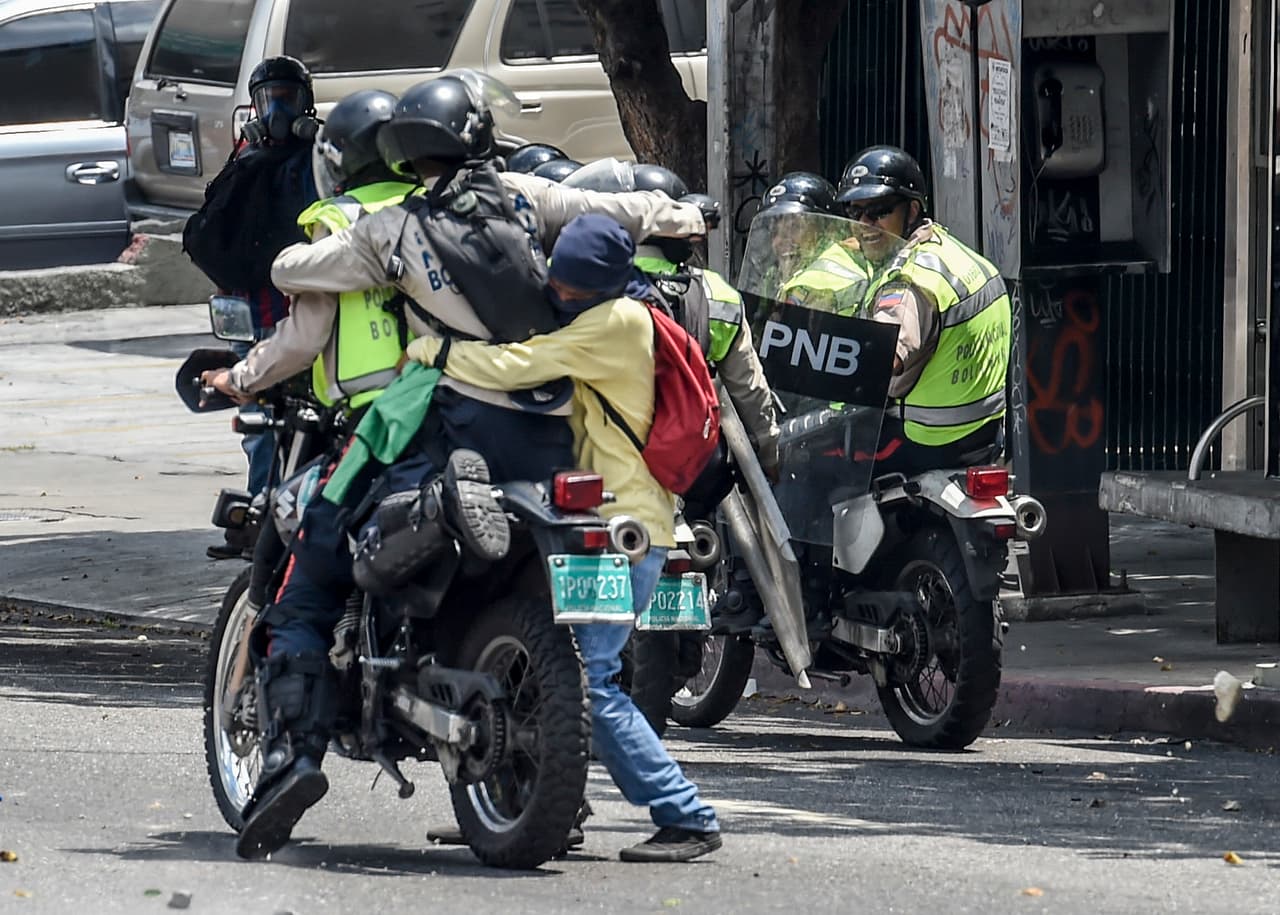 Un manifestante intenta bajar de la motocicleta a un policía. Caracas, 10 de abril de 2017.