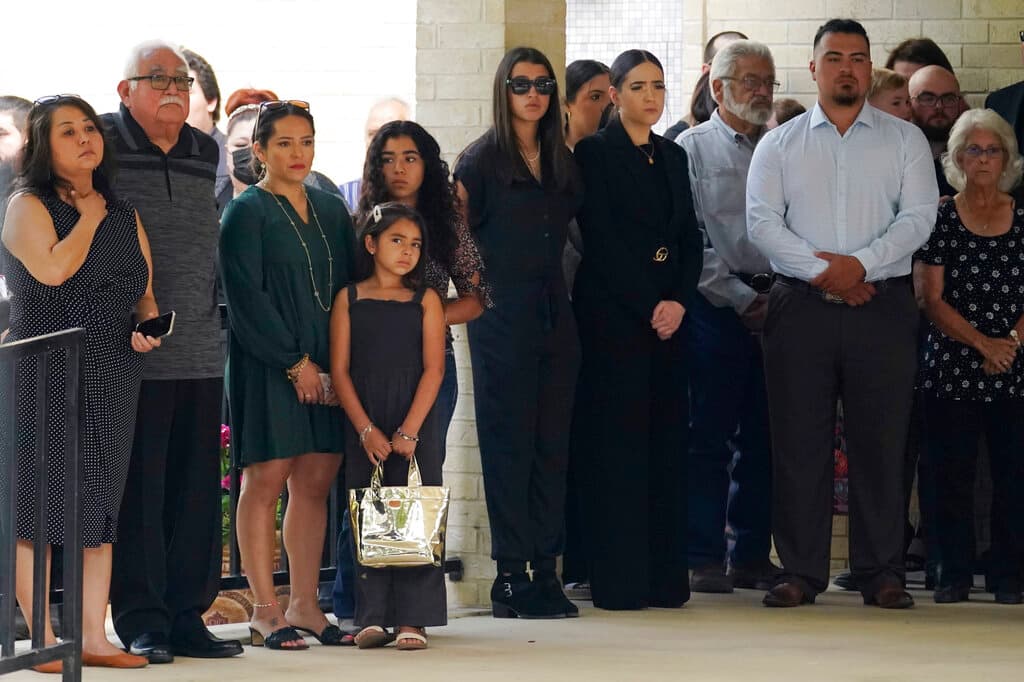 Los invitados observan cómo llegan los ataúdes para el servicio funerario conjunto.