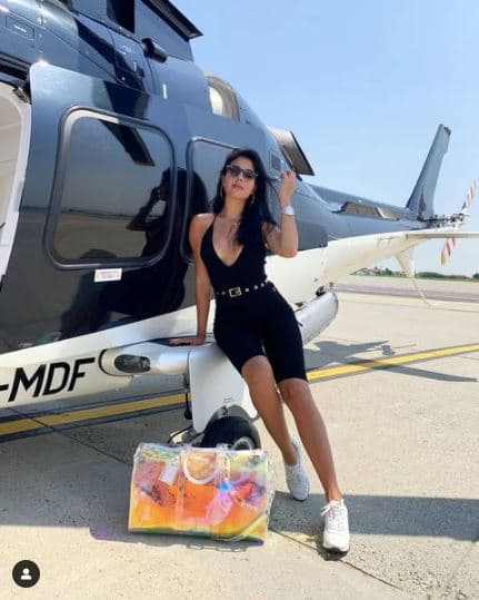 Esta maleta holográfica es un 
<b>Keepall Bandouliere</b>, diseñada en pvc iridiscente por el fallecido Virgil Abloh para Louis Vuitton. Se puede conseguir por unos $5,200 dólares.