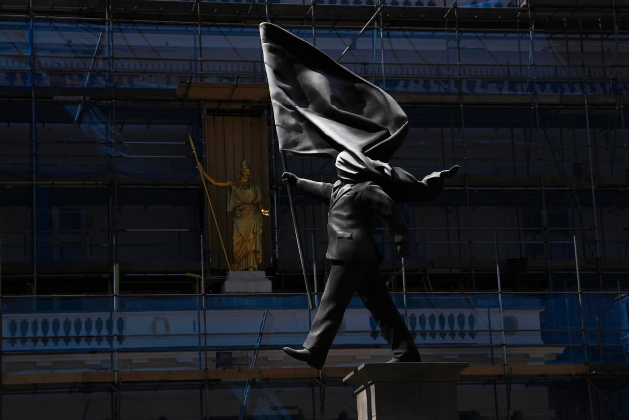 Una estatua de un hombre que sostiene una bandera que le cubre el rostro, firmada por Banksy, apareció en Waterloo Place, Londres, el jueves 30 de abril de 2026. (Foto AP/Kin Cheung)