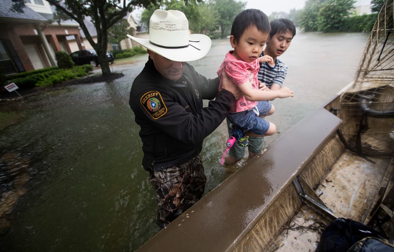 El alguacil del condado de Fort Bend, al oeste de Houston, ayuda a Lucas Wu y su hijo a evacuar la zona. El condado de Fort Bend está en peligro por la apertura de las compuertas de un reservorio de agua.