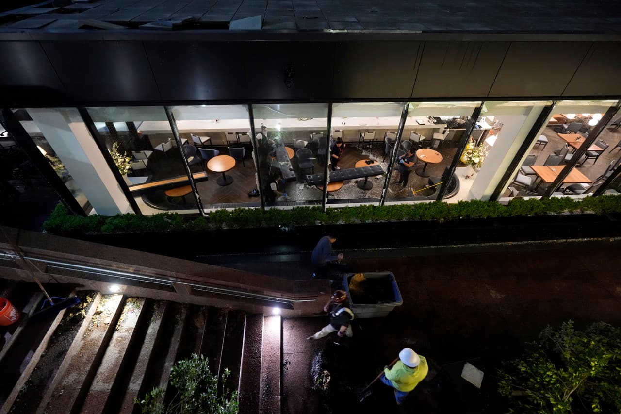 Trabajadores limpian dentro de un restaurante, donde las ventanas salieron volando en el centro de Houston.