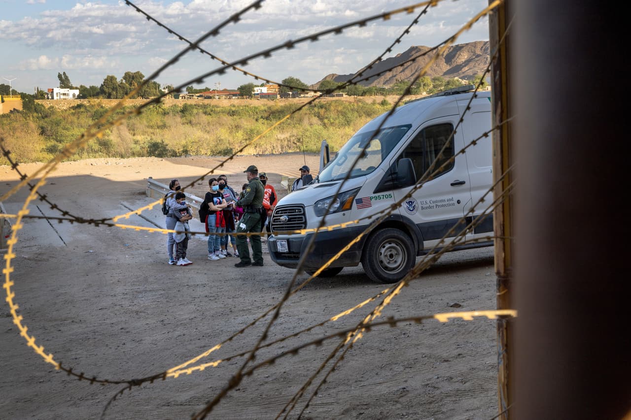 Un agente de la Patrulla Fronteriza se prepara para transportar a un grupo de inmigrantes cubanos desde la valla fronteriza al centro de procesamiento en Yuma, Arizona. Una familia había salido de su provincia central cubana de Camagüey casi tres semanas antes, volando a Nicaragua antes de viajar por tierra a través de América Central y México para llegar a los Estados Unidos en busca de asilo político.