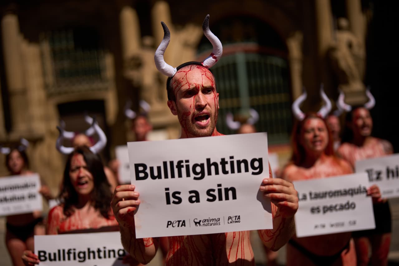 Un activistra hombre mantiene la frase de "La tauromaquia es un pecado" bañado en sangre y con cuernos
