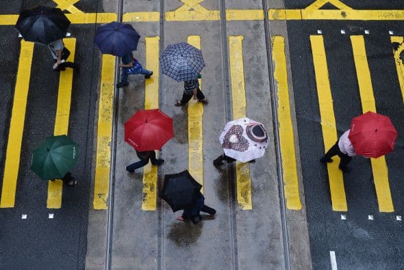 Transeúntes se protegen de la lluvia con sombrillas en una calle de Hong Kong.