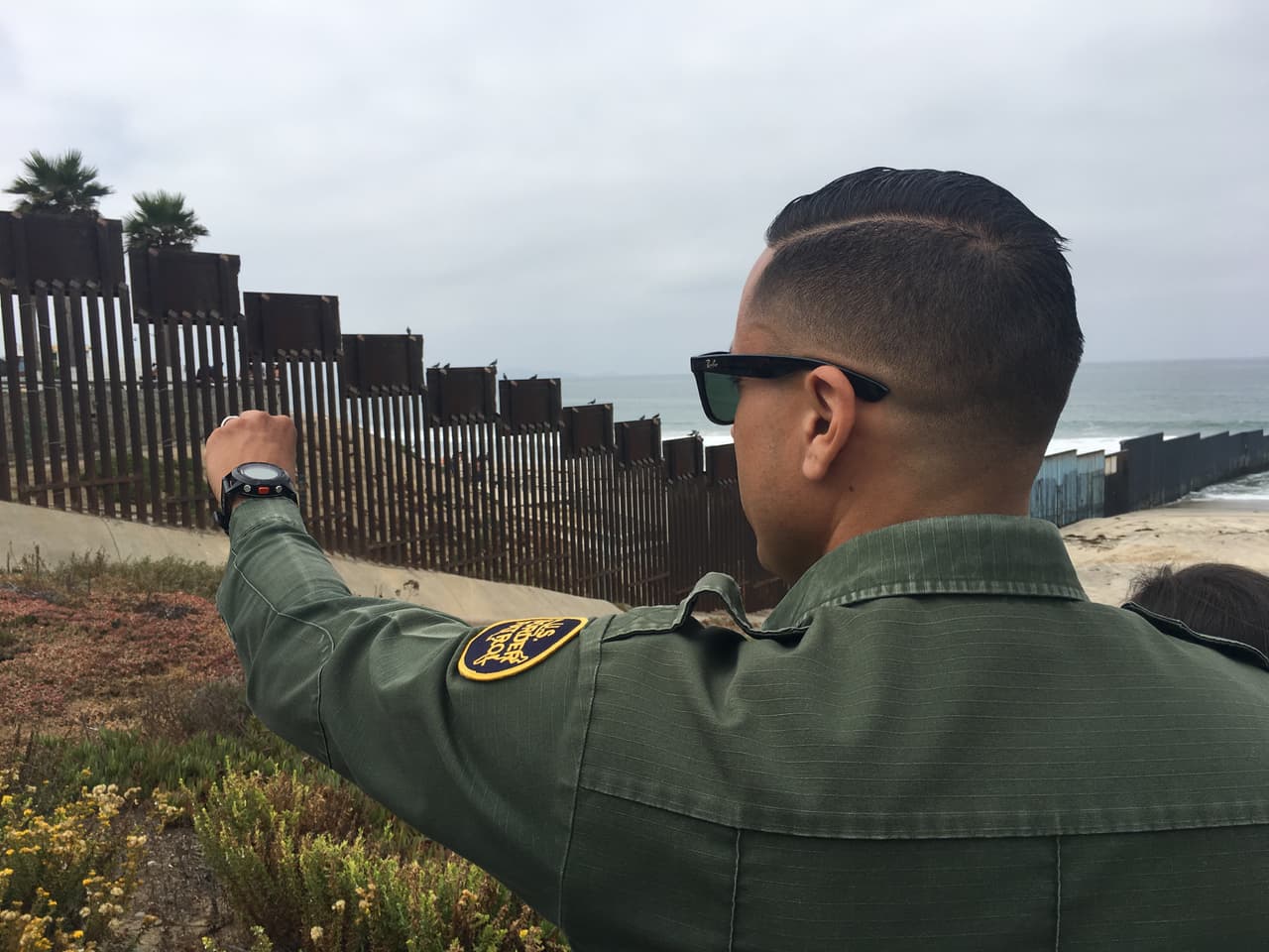 El agente Eduardo Olmos señala la zona cerca del Océano Pacífico donde cada fin de semana se reúnen decenas de familias de inmigrantes.