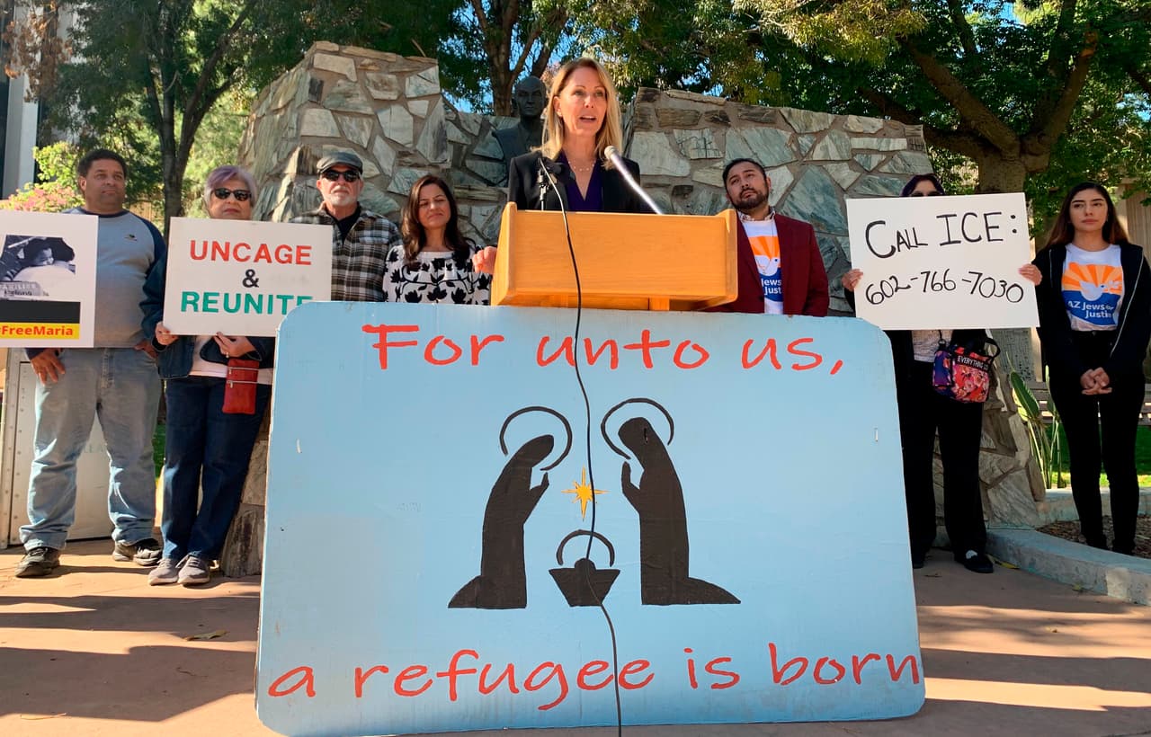 La representante Kelly Butler habla ante la prensa en Phoenix sobre el caso de una guatemalteca de 23 años que solicitó asilo y fue separada de su sobrina de 6 años. El letrero dice: "Nos ha nacido un refugiado". (AP Foto/Astrid Galvan)