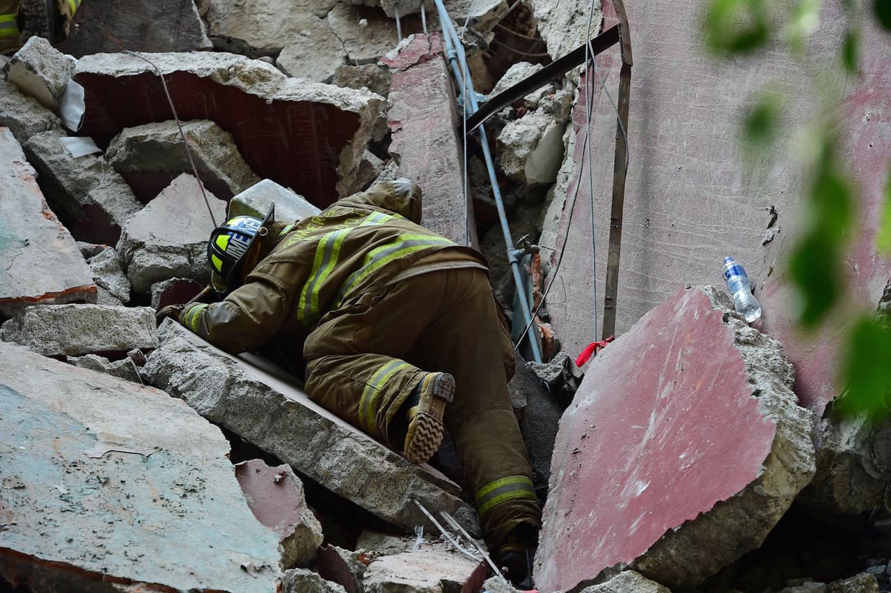TOPSHOT - Rescuers, firefighters, policemen, soldiers and volunteers remove rubble and debris from a flattened building in search of survivors after a powerful quake in Mexico City on September 19, 2017. A devastating quake in Mexico on Tuesday killed more than 100 people, according to official tallies, with a preliminary 30 deaths recorded in the capital where rescue efforts were still going on. / AFP PHOTO / RONALDO SCHEMIDT (Photo credit should read RONALDO SCHEMIDT/AFP/Getty Images)