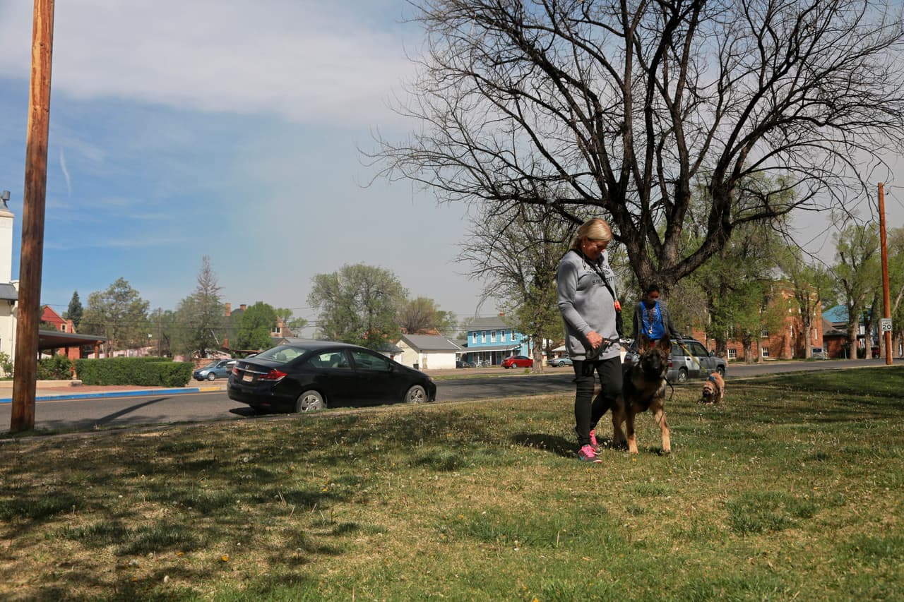 Liz Birmingham, de 66 años, pasea a su perro en Las Vegas, Nuevo México. Birmingham explicó que vivir en la ciudad es desconcertante, ya que el humo y el fuego fluctúan con los vientos, y algunos vecindarios han estado bajo avisos de evacuación. El cielo azul de la izquierda es típico de Nuevo México, mientras que la neblina de la derecha proviene del humo 
<a href="https://www.univision.com/noticias/estados-unidos/incendios-en-nuevo-mexico-miles-de-personas-evacuadas-fotos" target="_blank">de los incendios forestales</a> que han durado más de dos semanas.