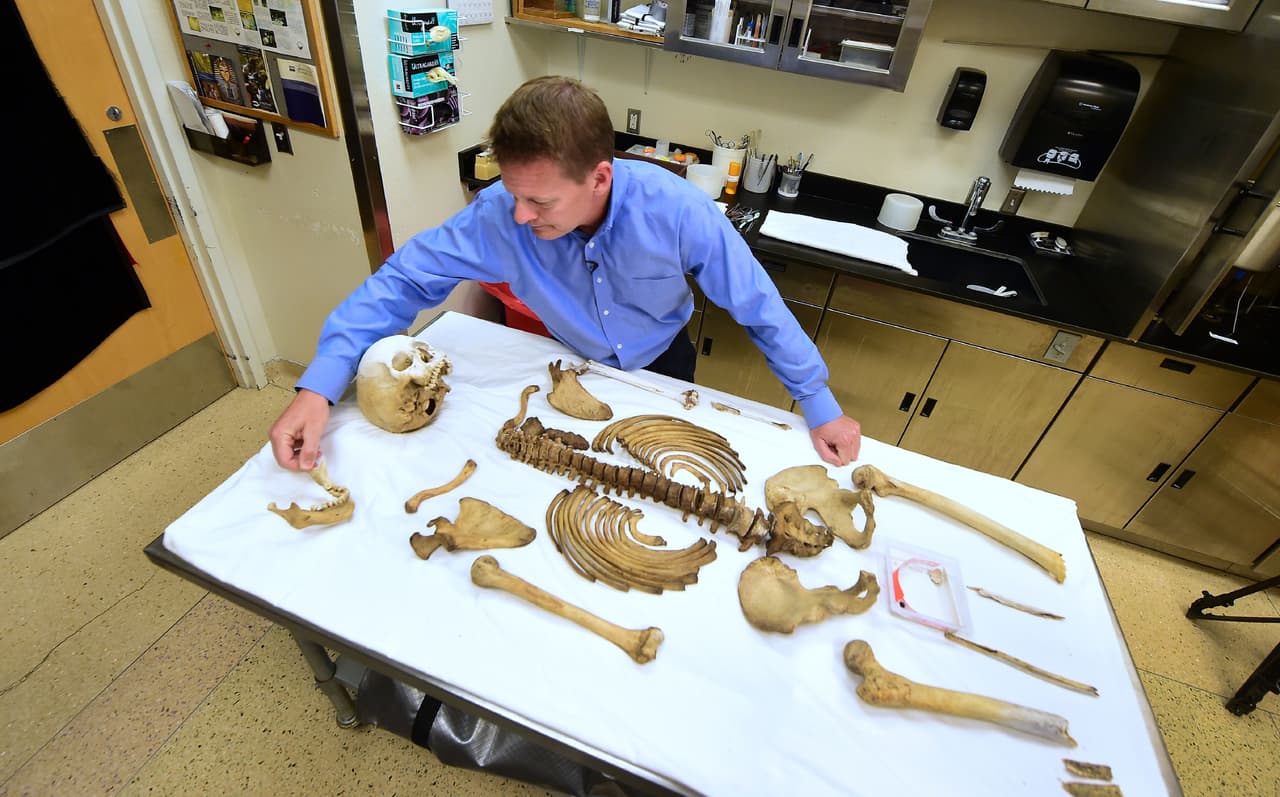 El Doctor Greg Hess, de la Oficina Forense del Condado Pima examina los restos de un inmigrante encontrado en el desierto.