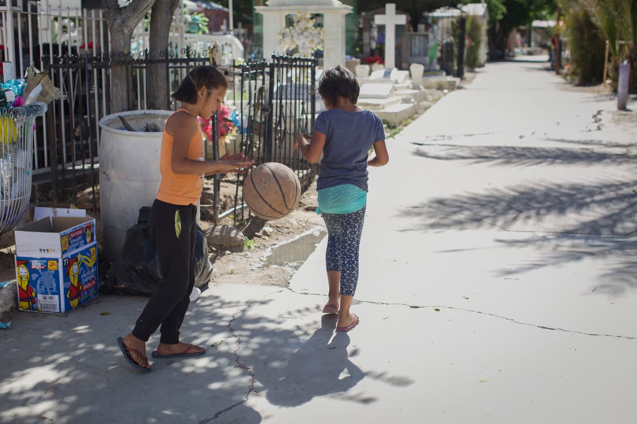 Alejandra (der), hija de Heidy Casco, y Sofía (izq), hija de otra migrante del grupo, juegan a la entrad del Panteón Nacional. No van a la escuela, pero se divierten jugando entre tumbas, dicen que son buenos escondites.