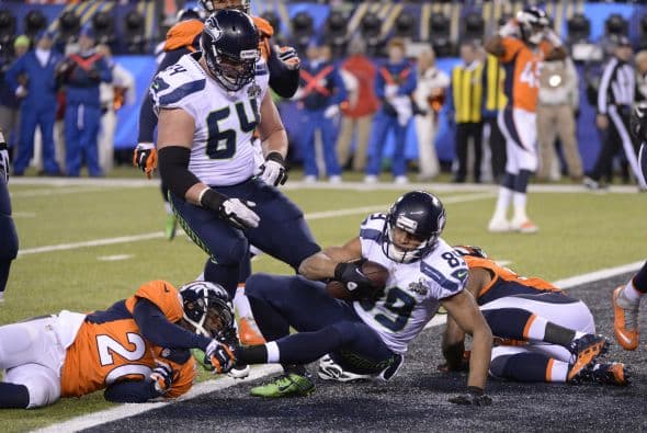 Los Seahawks, con un fútbol "total", el que había trabajado el entrenador del equipo durante toda la temporada regular, el veterano Pete Carroll, derrotaron por paliza de 43-8 a los Broncos, la mejor ofensiva de liga, con el mariscal de campo Peyton Manning a la cabeza. No habían pasado ni 12 segundos desde el comienzo del partido y los Seahawks ya hicieron historia con la anotación más rápida que se había dado jamás en un Super Bowl. Pero lo peor no fue el dejarse anotar dos puntos, sino la imagen de enfrentamiento entre Manning y el centro de origen mexicano Manny Ramírez, que no le dio bien al balón, y aunque el corredor Knowshon Moreno lo recuperó, lo hizo en la zona de protección. La mejor ofensiva de la NFL estaba paralizada, sin saber qué hacer, y ahí fue el comienzo y el final del partido disputado en el MetLife Stadium, de East Rutherford (Nueva Jersey), donde la temperatura fue de 43 grados. Malcom Smith recibió el premio de Jugador Más Valioso (MVP), el octavo defensor que lo consigue en un partido de Super Bowl y el tercer apoyador. Carroll, de 61 años, el tercer entrenador con más edad de la NFL que ganó un Super Bowl, se convirtió en el tercer entrenador que logra los dos títulos de campeón universitario de la NCAA con el equipo de USC y ahora los Seahawks en la NFL.