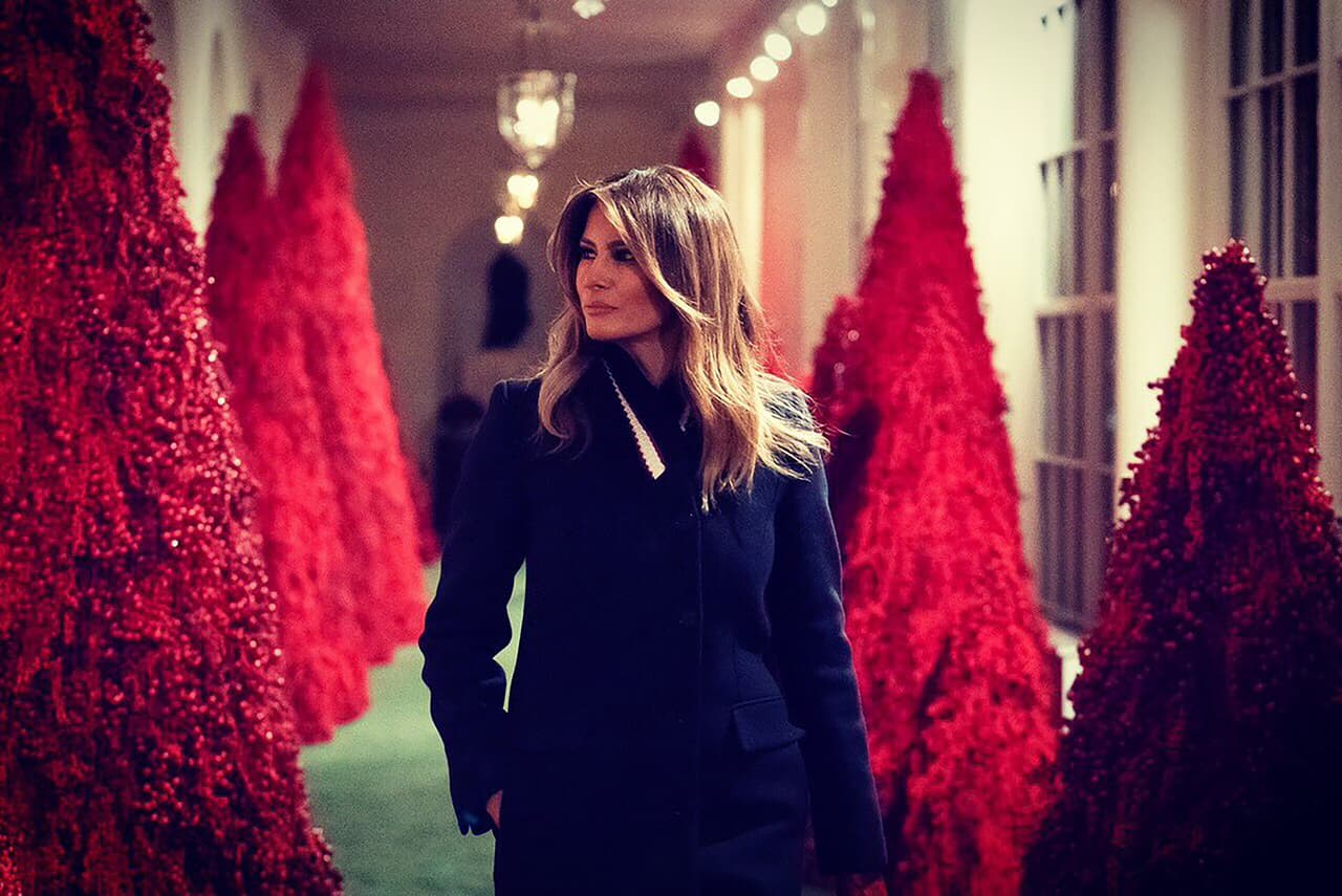 La primera dama publicó una fotografía de ella caminando por la columnata decorada con árboles rojos.
