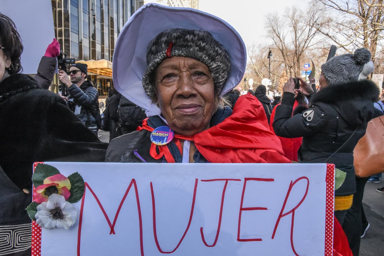 “Mujer”. Una activista por los derechos de las mujeres lleva un letrero en español en la marcha de Nueva York.