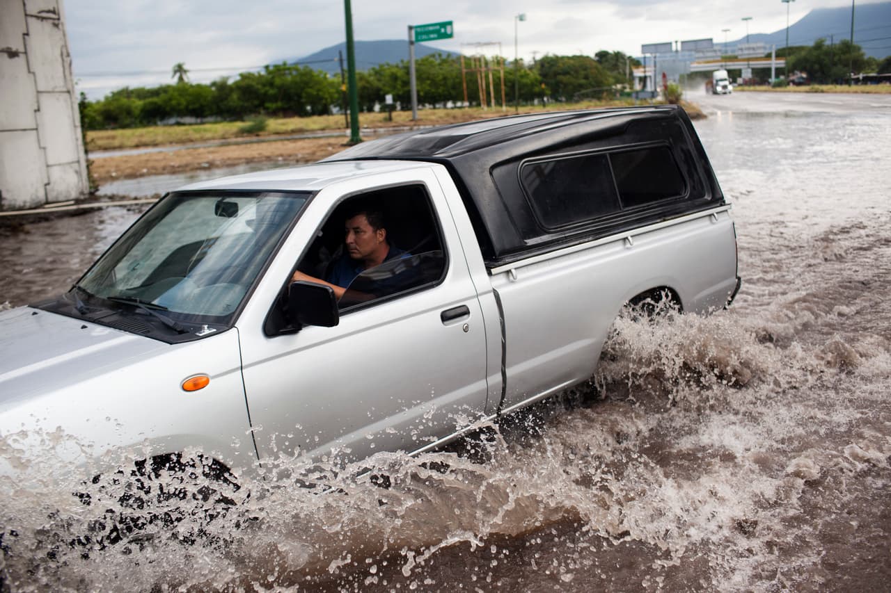 Un carro avanza por una calle inundada de Tecomán, Colima.