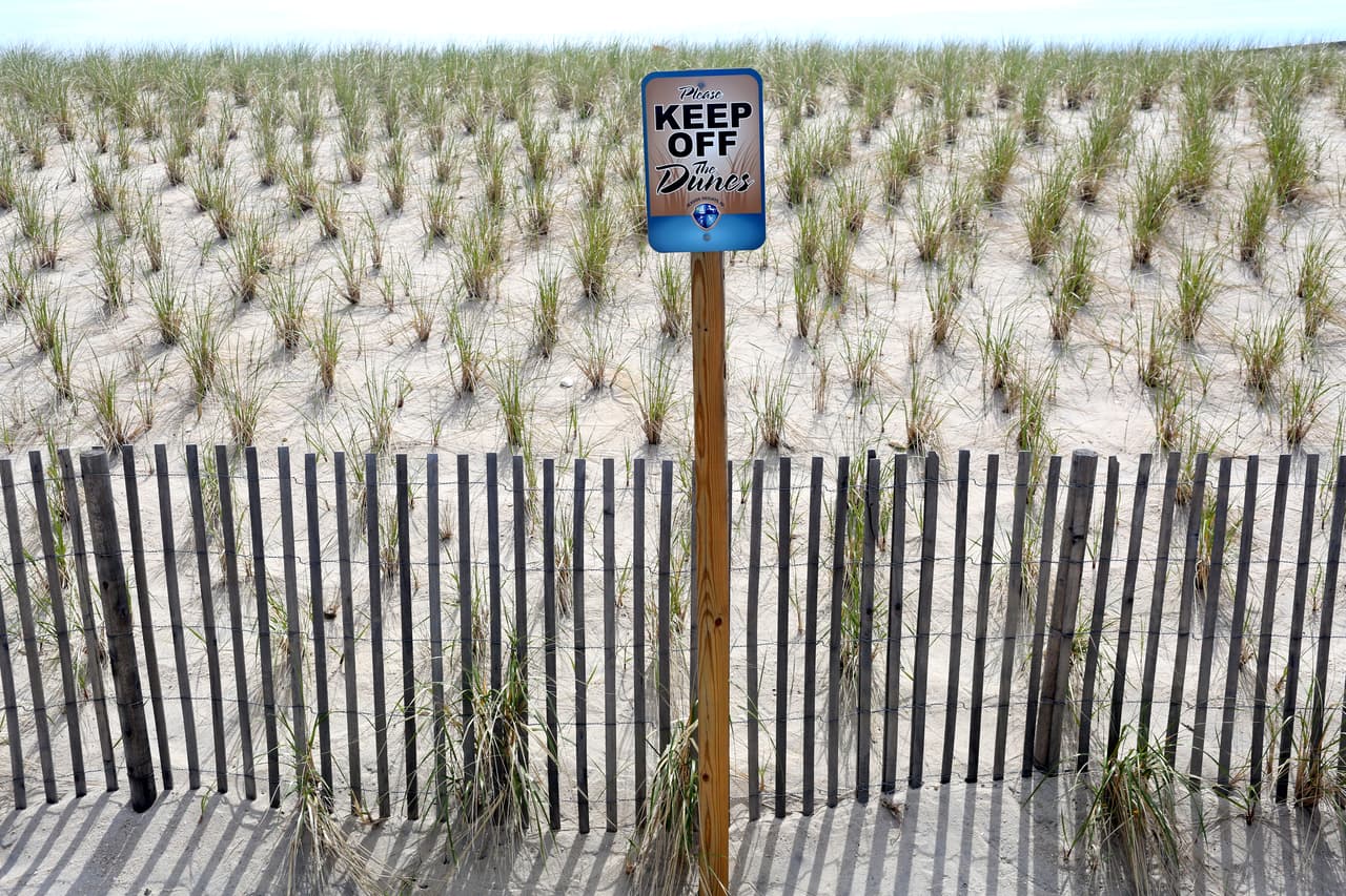 Un letrero pide a los transeúntes que se mantengan alejados de las dunas