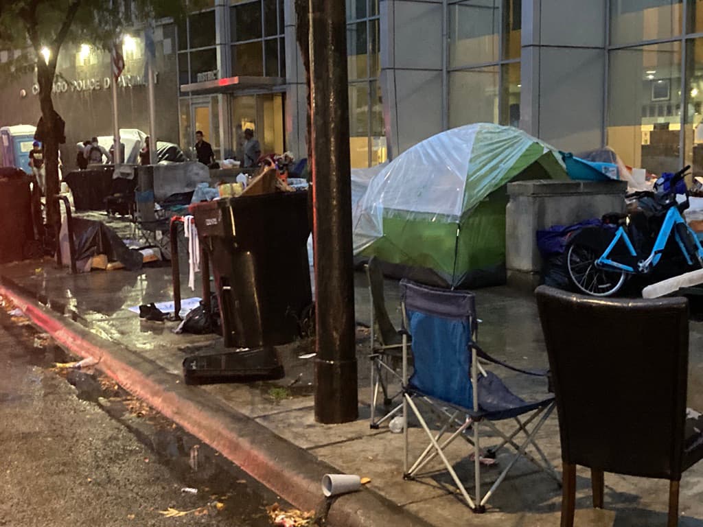El paso frente a la banqueta de la estación de policía está repleta de las pertenencias de migrantes.
