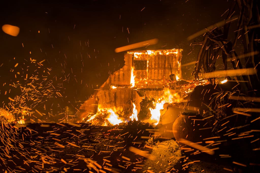 Los fuertes vientos avivan los brasas de casas en llamas durante el incendio de Woolsey, en Malibú. David McNew/Getty Images
