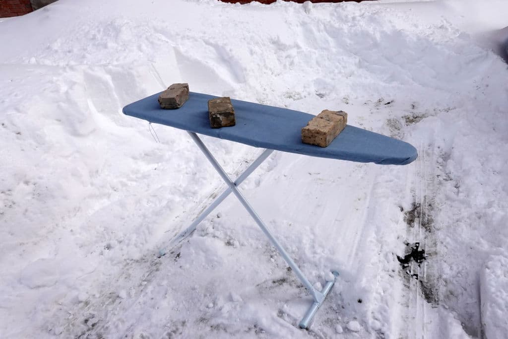 Un residente usa una tabla de planchar para guardar un lugar de estacionamiento en la calle después de palear la nieve. Un práctica que se conoce como "Dibs" en la ciudad.