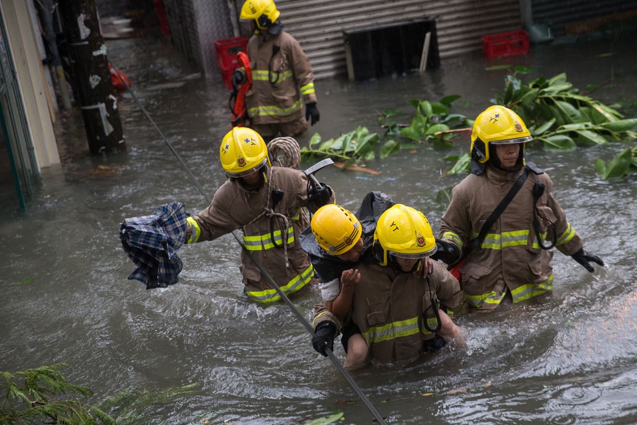 Hong Kong, China. Rescatistas llevan a una mujer en medio de las inundaciones. Los niveles de agua aumentaron 12 pies (3,5 metros) en algunos lugares, las olas inundaron las carreteras y arrojaron peces vivos a los caminos.