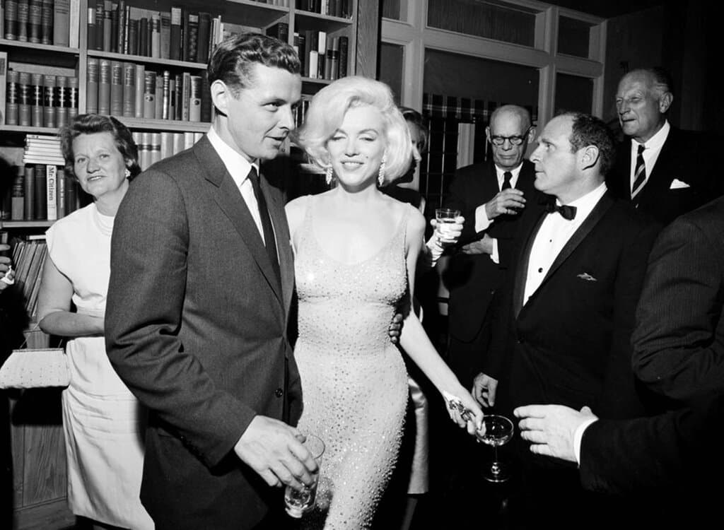 El 19 de mayo de 1962, poco más de dos meses antes de su muerte, el nombre de Marilyn Monroe resonó internacionalmente al 
<b>cantarle 'Happy Birthday'</b> al entonces 
<b>presidente John F. Kennedy</b>, en el Madison Square Garden, durante una recepción en la ciudad de Nueva York. 
<br>
<br>La foto, proporcionada por la Biblioteca y Museo Presidencial John F. Kennedy, muestra a la estrella del cine llevando 
<b><a href="https://www.univision.com/estilo-de-vida/trending/el-vestido-con-el-que-marilyn-monroe-canto-cumpleanos-feliz-a-jfk-se-ha-vendido-por-48-millones-de-dolares" target="_blank">un vestido que robó suspiros</a></b>, en compañía de Steve Smith, cuñado del presidente Kennedy.