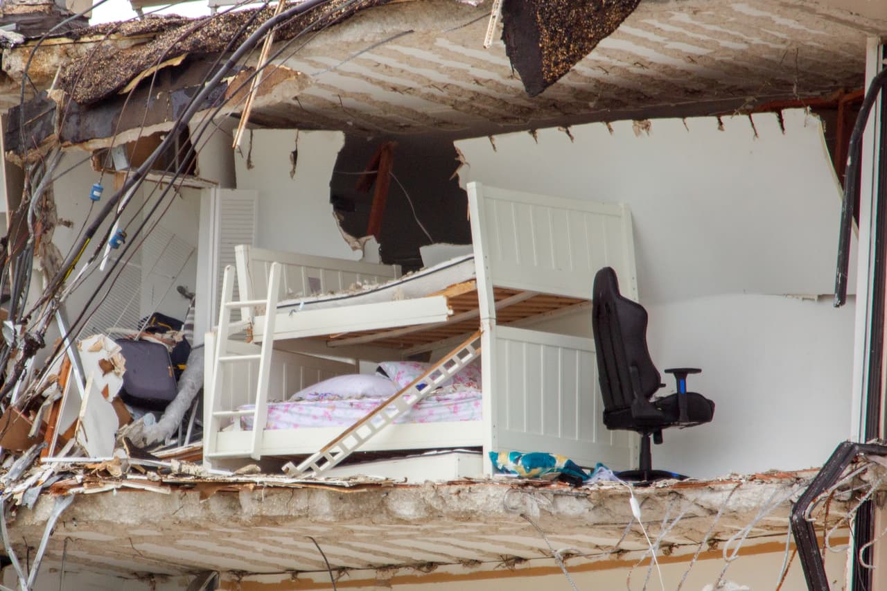 Esta litera junto a una silla de oficina está en las ruinas del apartamento donde vivía Linda March, una de las personas que aún se encuentra desaparecida. Según la agencia AP, March tenía alquilado el penthouse cuatro del piso 12 del edificio, y utilizaba este dormitorio amoblado con una litera como oficina. 
<br>
<br>March tenía 58 años, era abogada, no tenía hijos y estaba divorciada. Según Rochelle Laufer, una amiga que fue entrevistada por la agencia AP, su vida frente al mar en Surfside significó un nuevo comienzo. Vivía en un pequeño apartamento de Nueva York y sobrevivió al 
<a href="https://www.univision.com/temas/coronavirus"><u>covid-19</u></a> antes de mudarse a Florida. 
<br>
<br>Aunque disfrutaba la vida frente al Atlántico no estaba a gusto con el ruido de las construcciones cercanas, contó Laufer. Estaba buscando un lugar para mudarse.
<br>