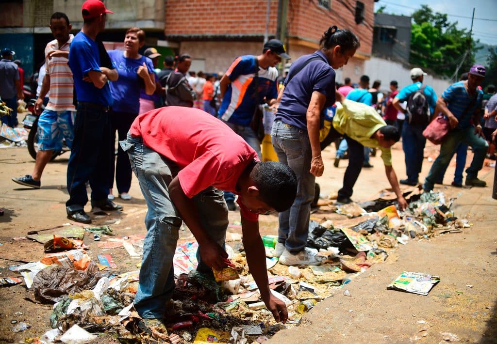 Los residentes de El Valle, en Caracas, buscan comida entre los restos que quedaron en el suelo tras el saqueo del pasado 21 de abril.