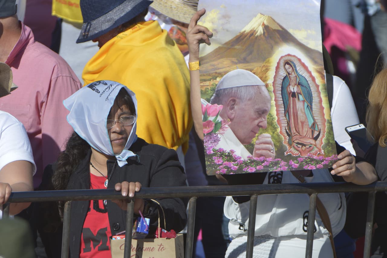 Fieles asisten a la misa en Ciudad Juárez con pósters del Papa.