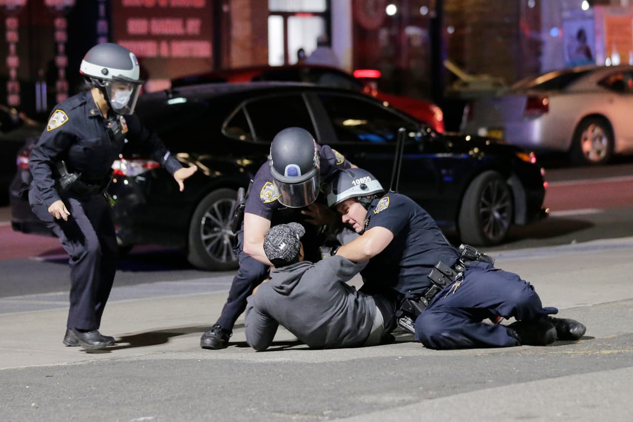 Agentes de la Policía de Nueva Yrok inmovilizan a un presunto saqueador en Manhattan. La limitación al movimiento de los 8.6 millones de habitantes de la ciudad más grande del país se suma a las restricciones impuestas por el coronavirus.