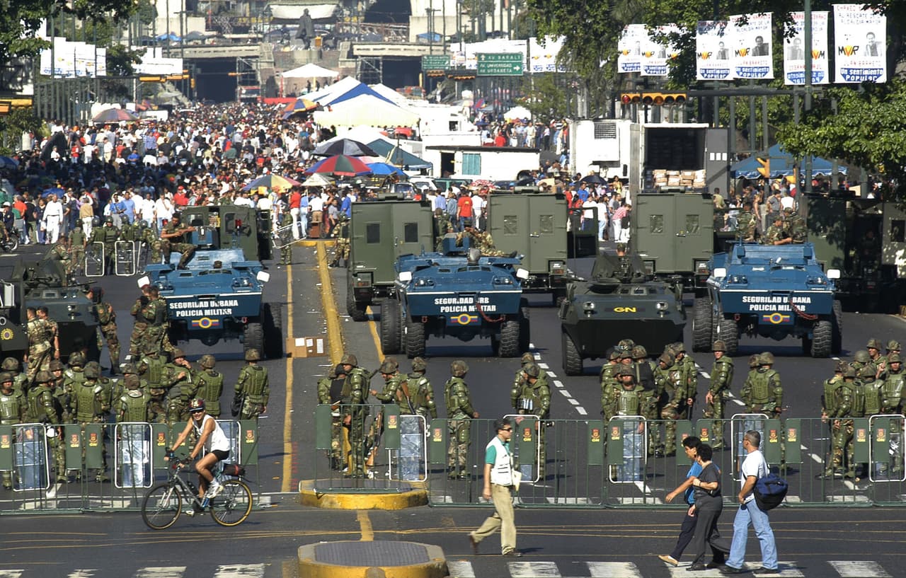 El expresidente Hugo Chávez empezó a dar control a los militares sobre la comida y la economía en general, tras intentos de la oposición de derrocarlo en 2002. En esta imagen de archivo del 14 de febrero de 2004, el ejército crea un perímetro en un mercado de comida subvencionado por el estado en la capital, Caracas.