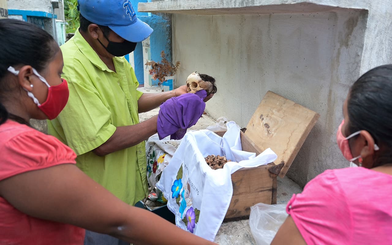 En la imagen, tomada a mediados de octubre, se observa a miembros de la comunidad preparar los restos de sus seres queridos para la celebración. El clima húmedo y nublado de la región en esta época del año acompaña al ritual.