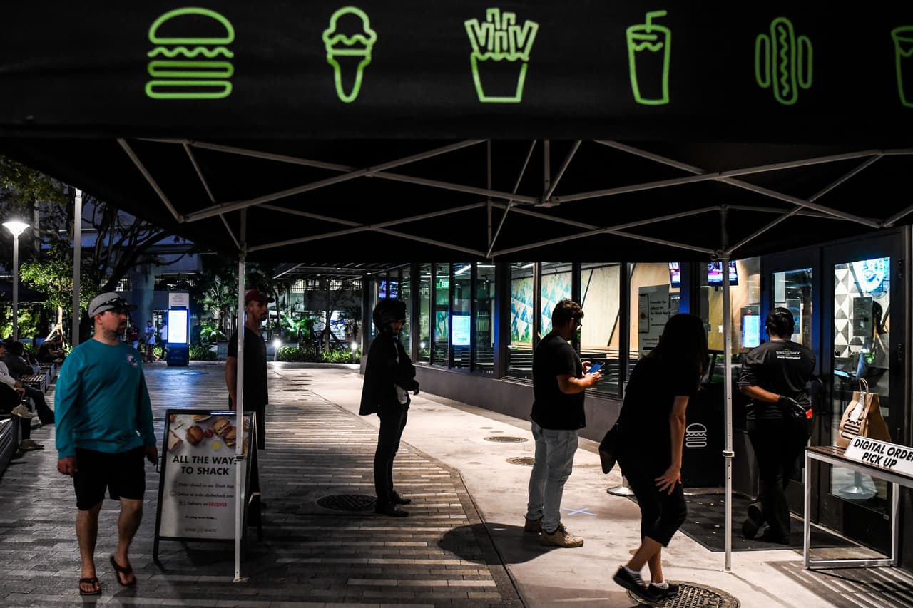 Unos pocos salen a pedir sus órdenes de comida a domicilio, manteniendo la distancia social, que ordenan las autoridades, para evitar la propagación del coronavirus.