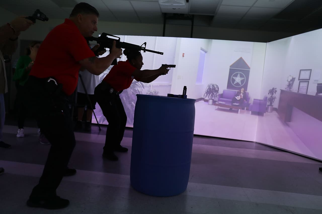 Los entrenadores de la policía de Miami, Luis González y Yolando Jones, interactúan con el sistema durante la simulación de un tiroteo en una oficina y utilizan armas cortas y largas.