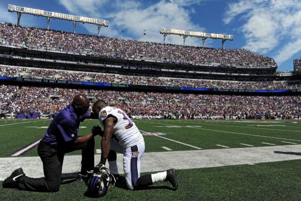 El corredor Lorenzo Taliaferro de los Cuervos de Baltimore ora con un entrenador antes de jugar contra los Cincinnati Bengals en el M&T Bank Stadium el 7 de septiembre de 2014 en Baltimore, Maryland.