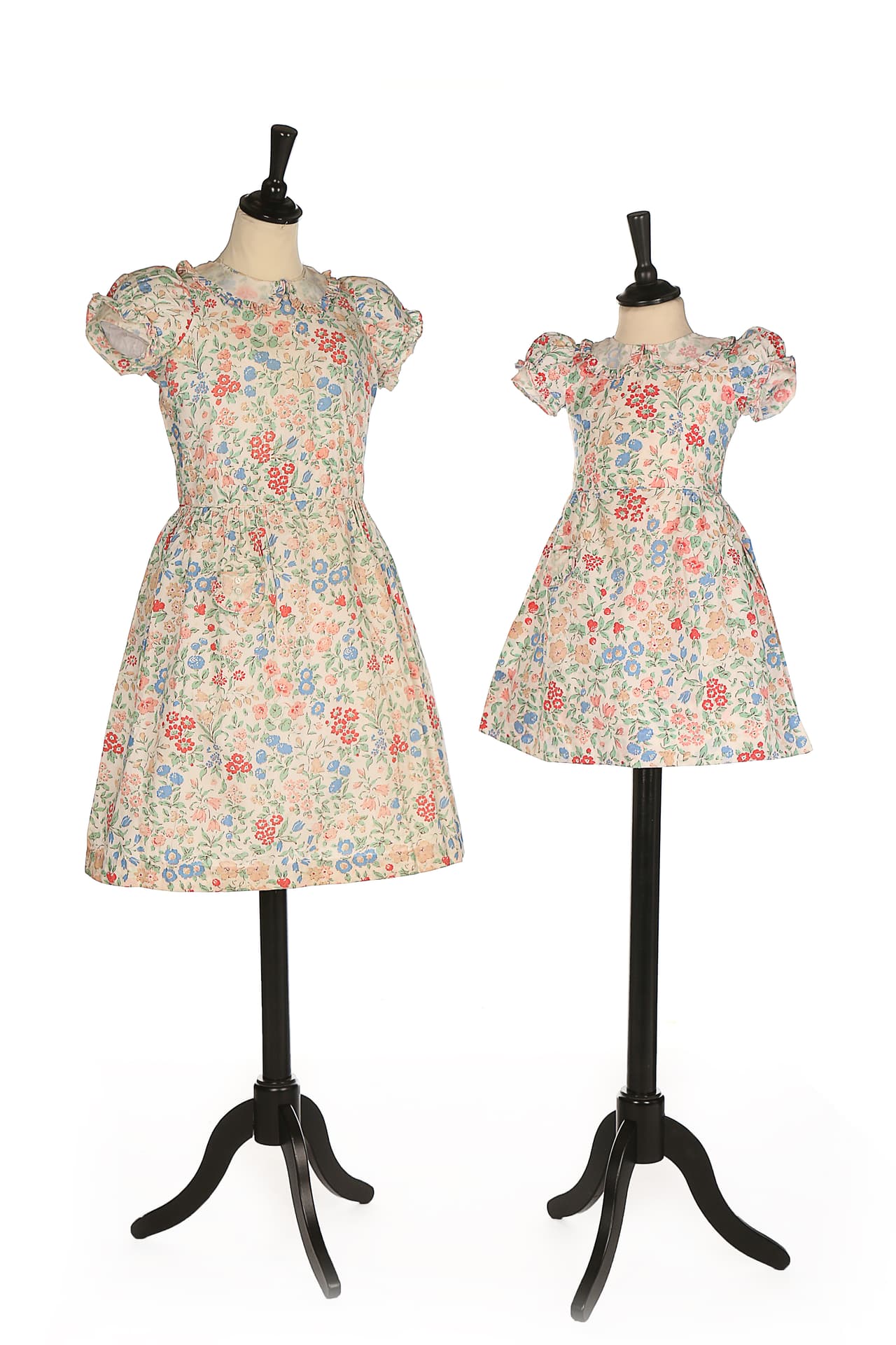 Las pequeñas Isabel y Margarita vistieron 
<b>estos trajes de algodón</b> con estampado floral en 1936. Ese año su padre
<b> Jorge VI</b> se convirtió en
<b> rey de Inglaterra</b> y su madre Isabel en la
<b> reina consorte</b>. De diseño similar, ambos vestidos tienen un cuello estilo ‘Peter Pan’, mangas abullonadas y bolsillos en la falda.