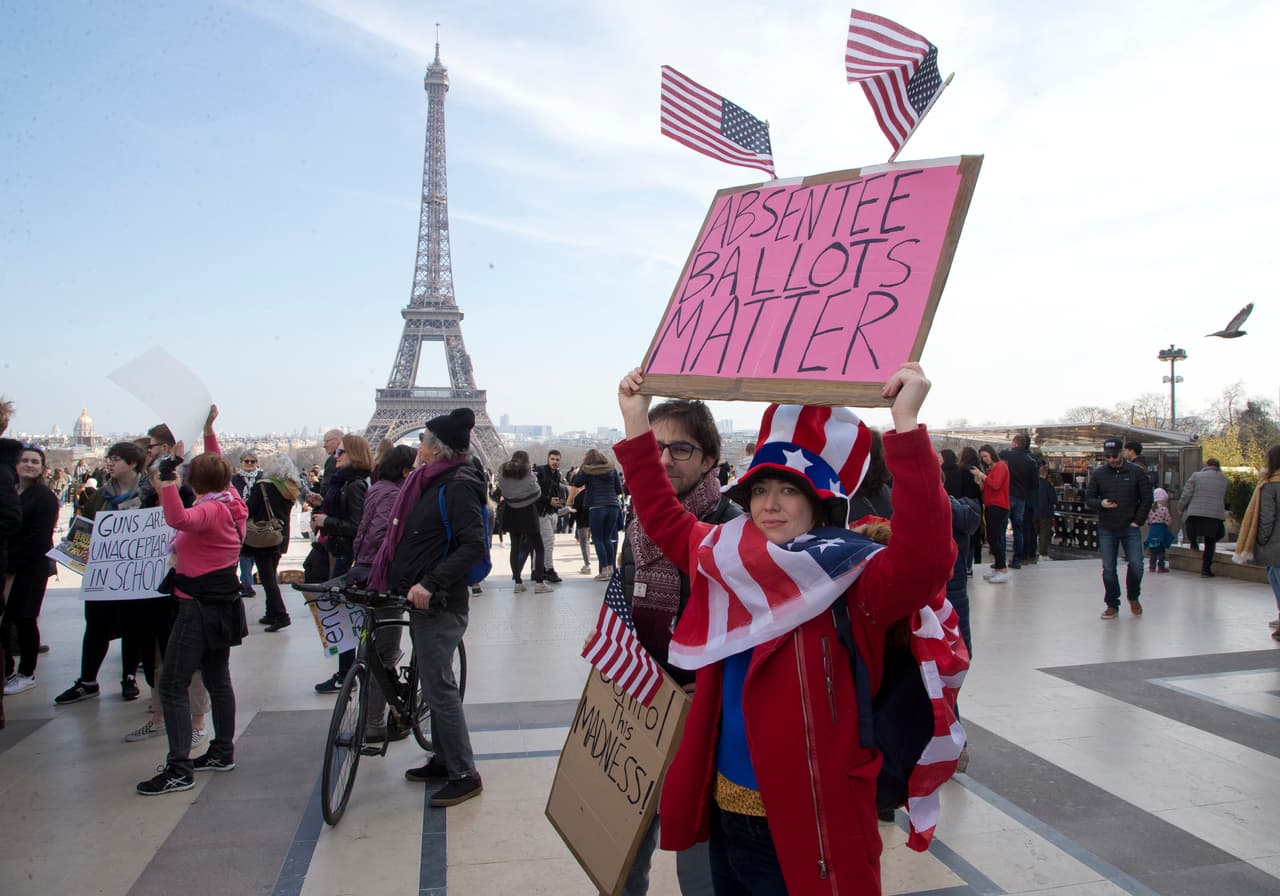 <b>París, Francia.</b> Activistas por el control de armas manifiestan con pancartas y banderas de EEUU frente a la torre Eiffel.