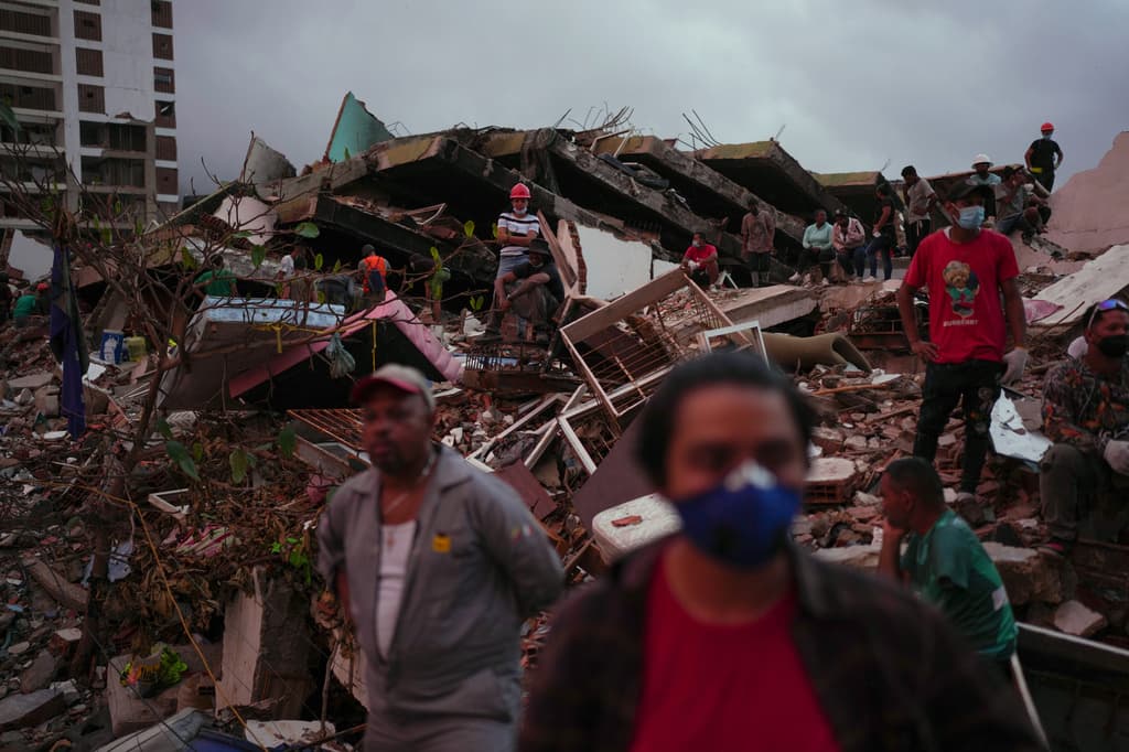 Personas observan a los equipos de rescate realizar labores de búsqueda y salvamento para llegar a posibles supervivientes tras los terremotos que sacudieron La Guaira, Venezuela, el martes 30 de junio de 2026. (Foto AP/Matias Delacroix)
