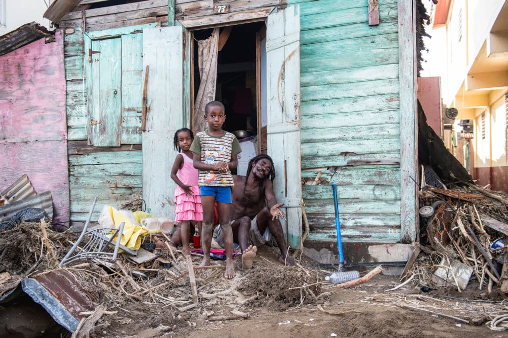 A family stand outside their house in Roseau, on the Caribbean island of Dominica, on September 22, 2017, after Hurricane Maria hit the island. Hurricane Maria left more than 15 people dead in hard-hit Dominica, the small Caribbean island's Prime Minister Roosevelt Skerrit announced on Thursday. The hurricane devastated the island, which has some 72,000 inhabitants and was hit by the storm on September 18 when it was at the height of its Category Five power. / AFP PHOTO / Lionel CHAMOISEAU (Photo credit should read LIONEL CHAMOISEAU/AFP/Getty Images)