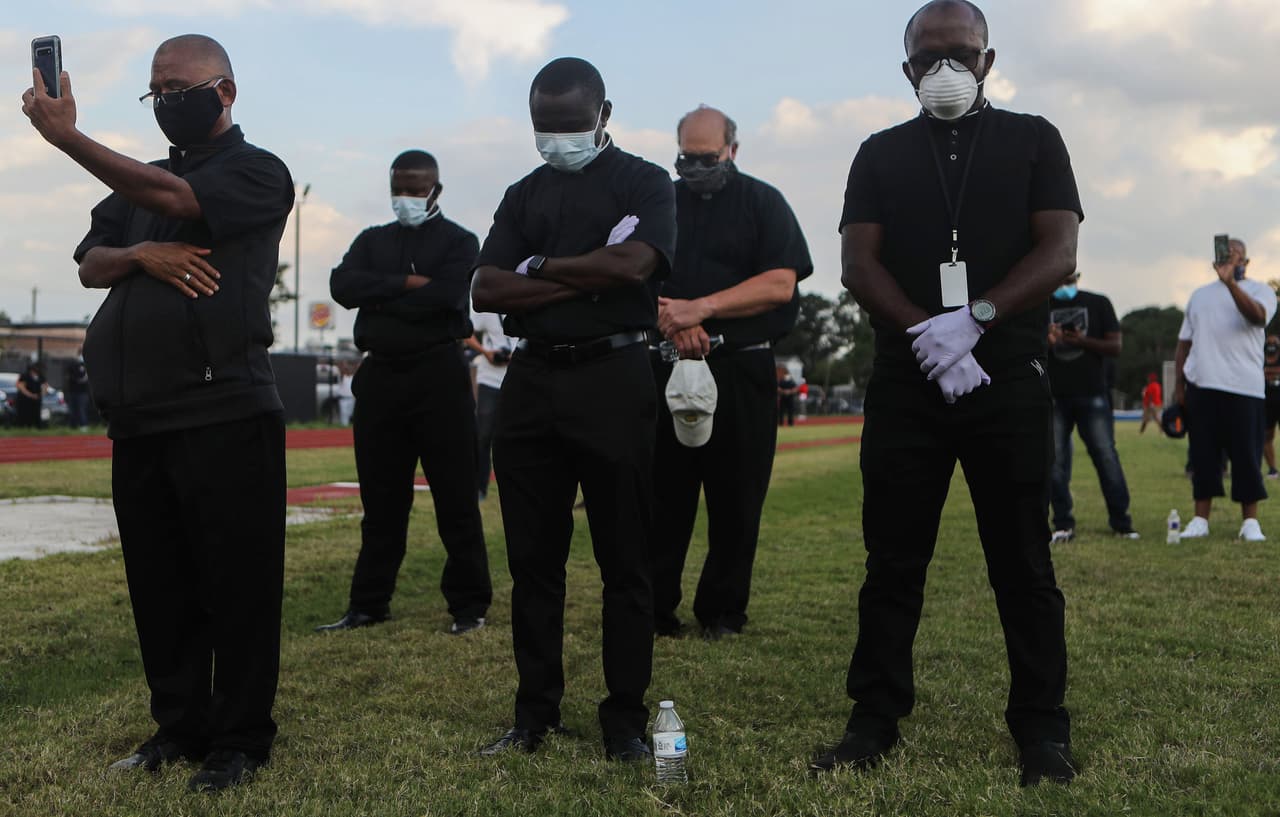 Clérigos de pie en una vigilia en honor a George Floyd en el campo de fútbol de la Escuela Secundaria Jack Yates el 8 de junio de 2020 en Houston, Texas.