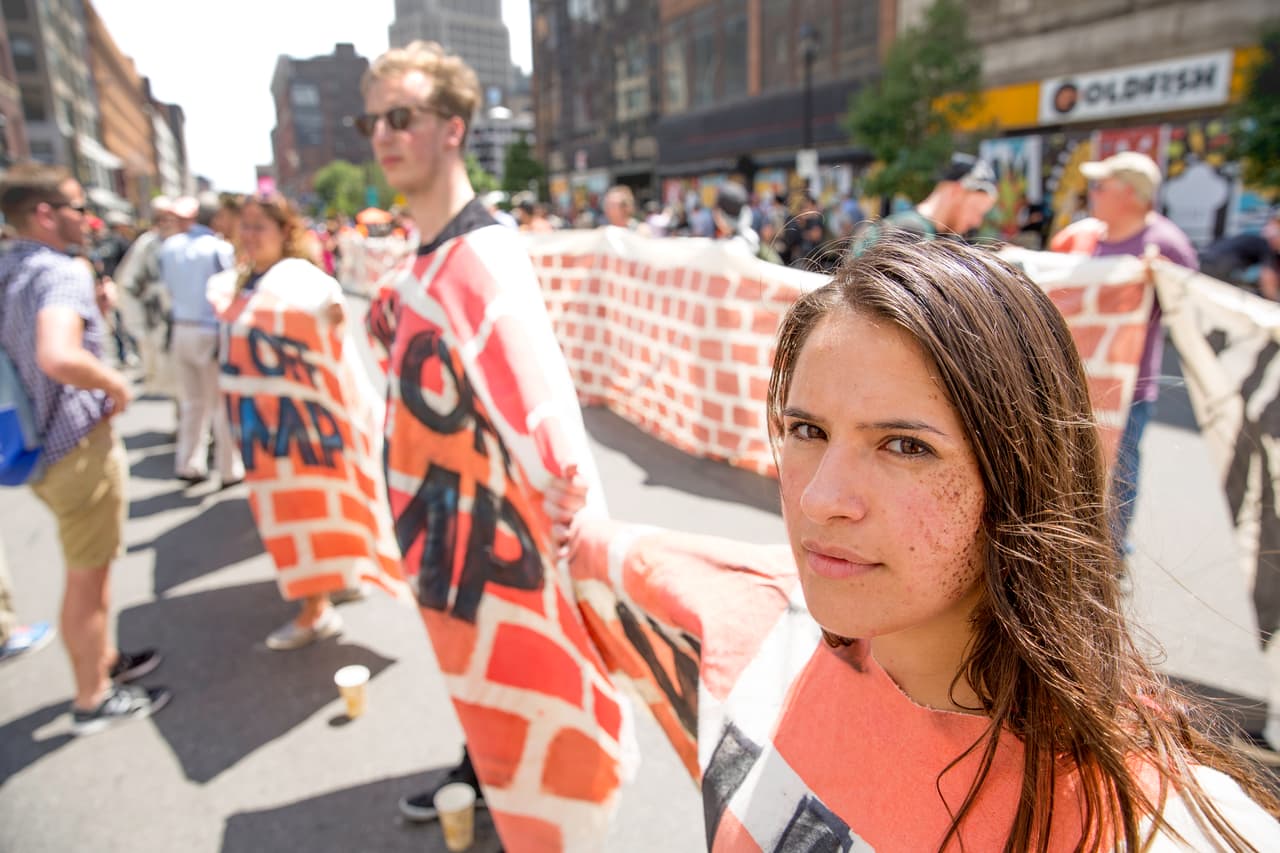 MIERCOLES 20 DE JULIO. 12:37 PM. El muro, hecho de tela y pintado a mano, fue extendido por varias calles del centro de Cleveland y trasladado desde la entrada del Quicken Loans Arena al Public Square. En primer plano la manifestante Gilliam Sorensky, de la ciudad, participa en el evento para apoyar a los inmigrantes.