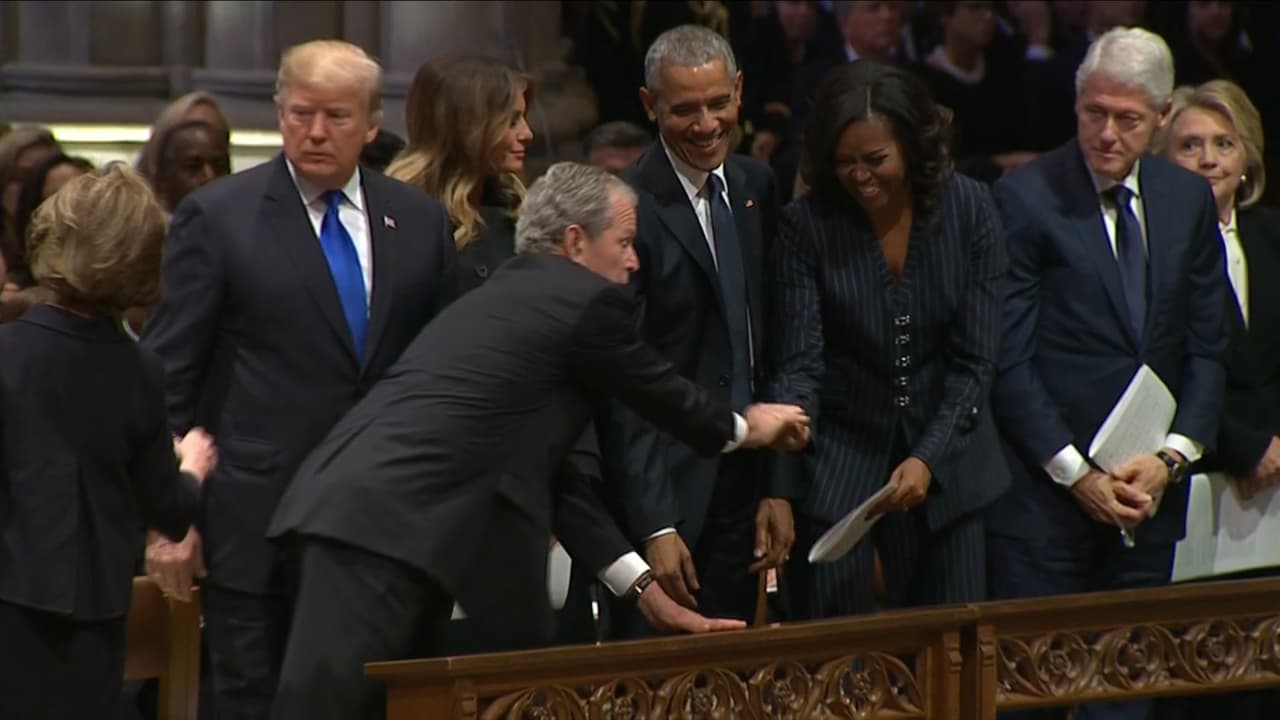 Michelle Obama no pudo contener la risa. En medio del solemne funeral del expresidente George H. W. Bush, su hijo, el también expresidente George W. Bush se acercó a la banca en donde estaban sentados los exmandatarios junto a sus esposas, y después de saludarlos a todos, estiró la mano y le entregó algo a Michelle Obama –que pudo ser un caramelo dulce o quizás para la tos, según reportes– un gesto que desató camaradería y risa entre sus testigos.