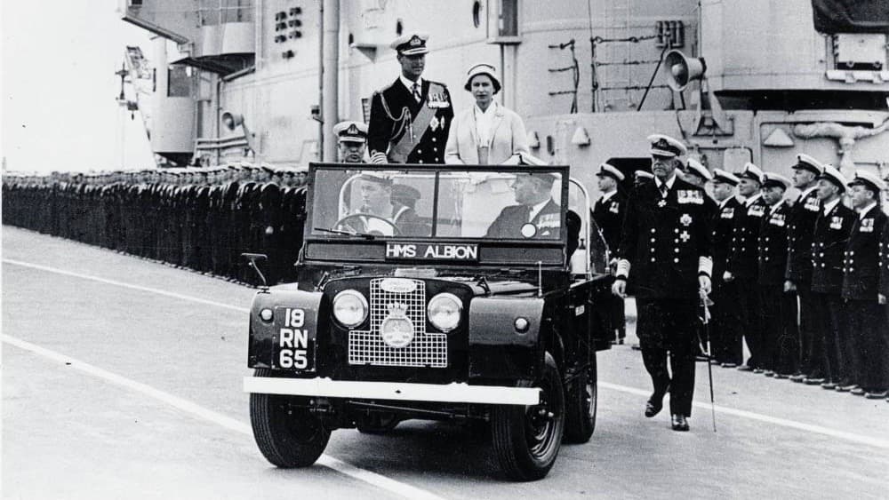 La reina Isabel II y el príncipe Felipe a bordo de una Land Rover Serie I pasan revista a las tropas a bordo del portaaviones HMS Albion en mayo de 1957 en Escocia.