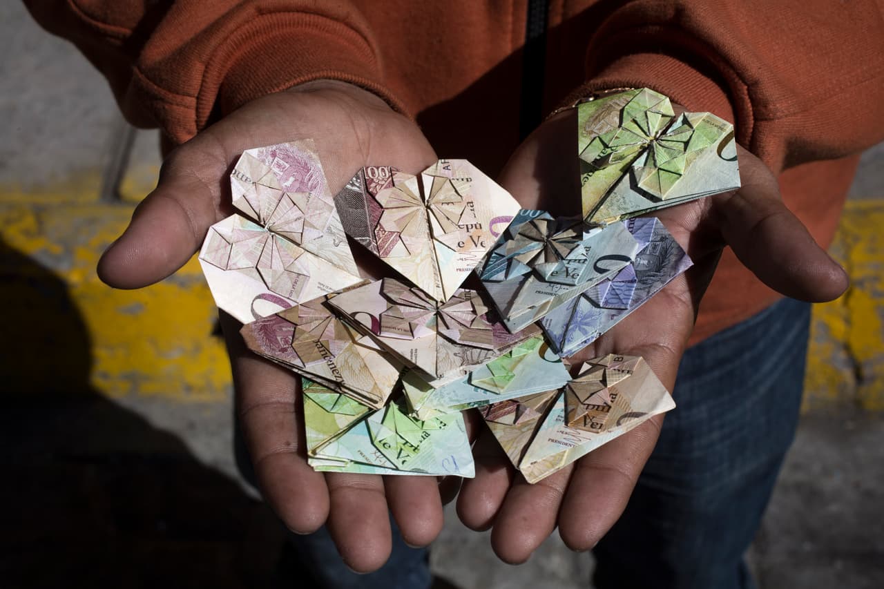 Enrique hace corazones con los bolívares que trajo de Venezuela que valen menos que el papel. Con la venta, pretende conseguir dinero para seguir su viaje.