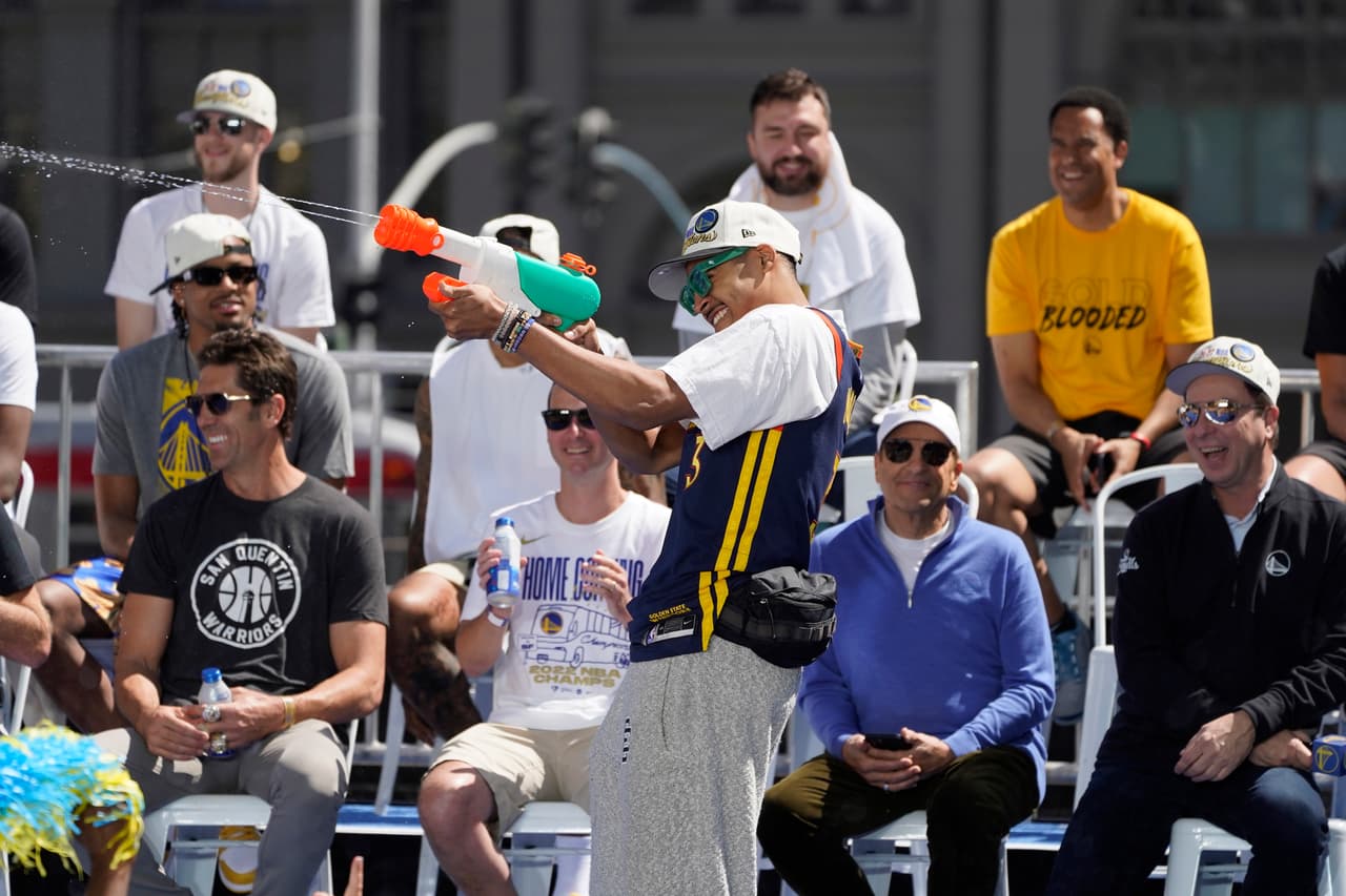 Jordan Poole, de los Golden State Warriors, rocía agua a la multitud antes del inicio del desfile por el campeonato de la NBA en San Francisco, el lunes 20 de junio de 2022. (Foto AP/Eric Risberg)