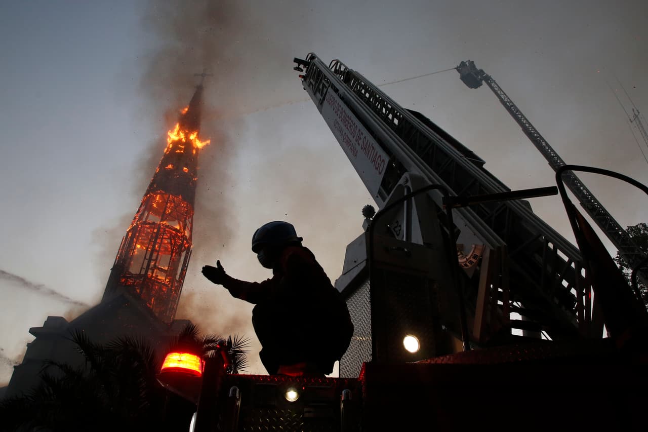 La iglesia de La Asunción en llamas durante una protesta en Santiago de Chile, el 18 de octubre. Una manifestación pacífica bajo estricta vigilancia policial se salió de control y un grupo de encapuchados arremetieron contra dos templos del centro de la capital chilena.
<br>