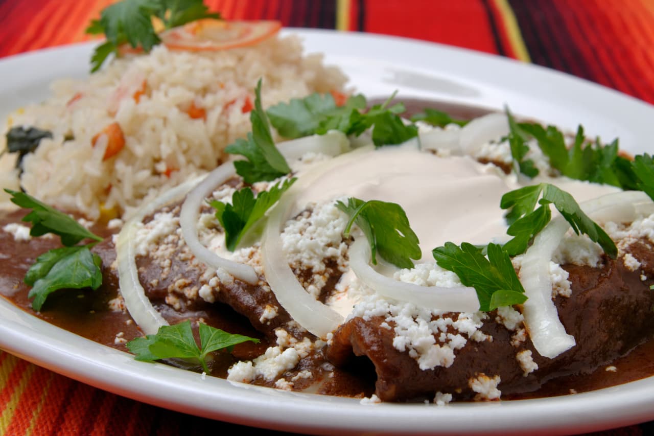 El tradicional platillo es acompañado de cebolla fresca picada o en rodajas, lechuga, crema de leche y mucho queso.